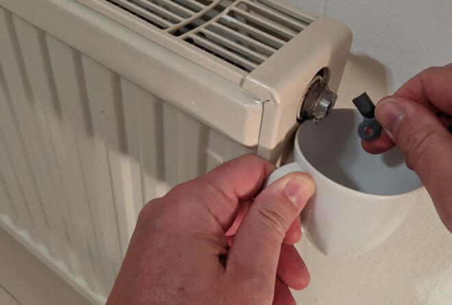 Heizkörper entlüften mit Schlüssel und Tasse